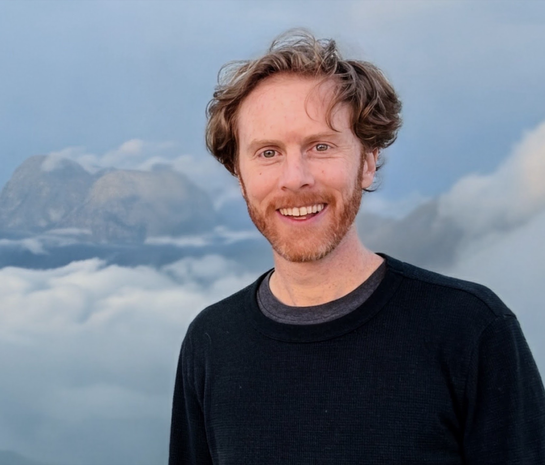 Bryan Hermannsson smiling in front of misty mountains