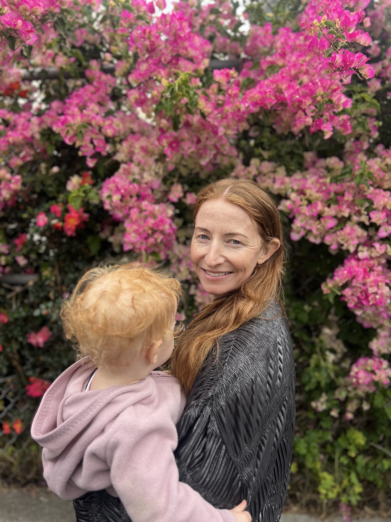 Tricia Sweeney holding her daughter in front of pink flowers
